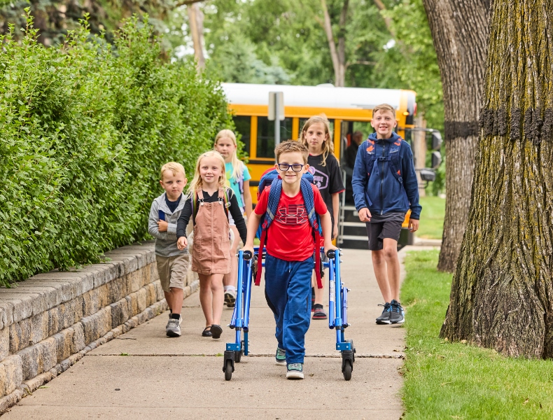 Kids walking on the sidewalk to school.