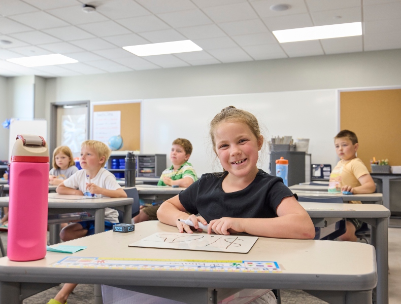 Student at a desk smiling.