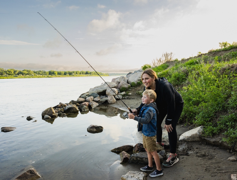 Women and child fishing along the shore.