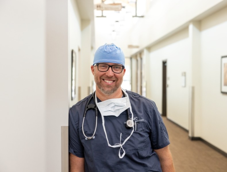 Medical professional leaning on a wall in the hallway.